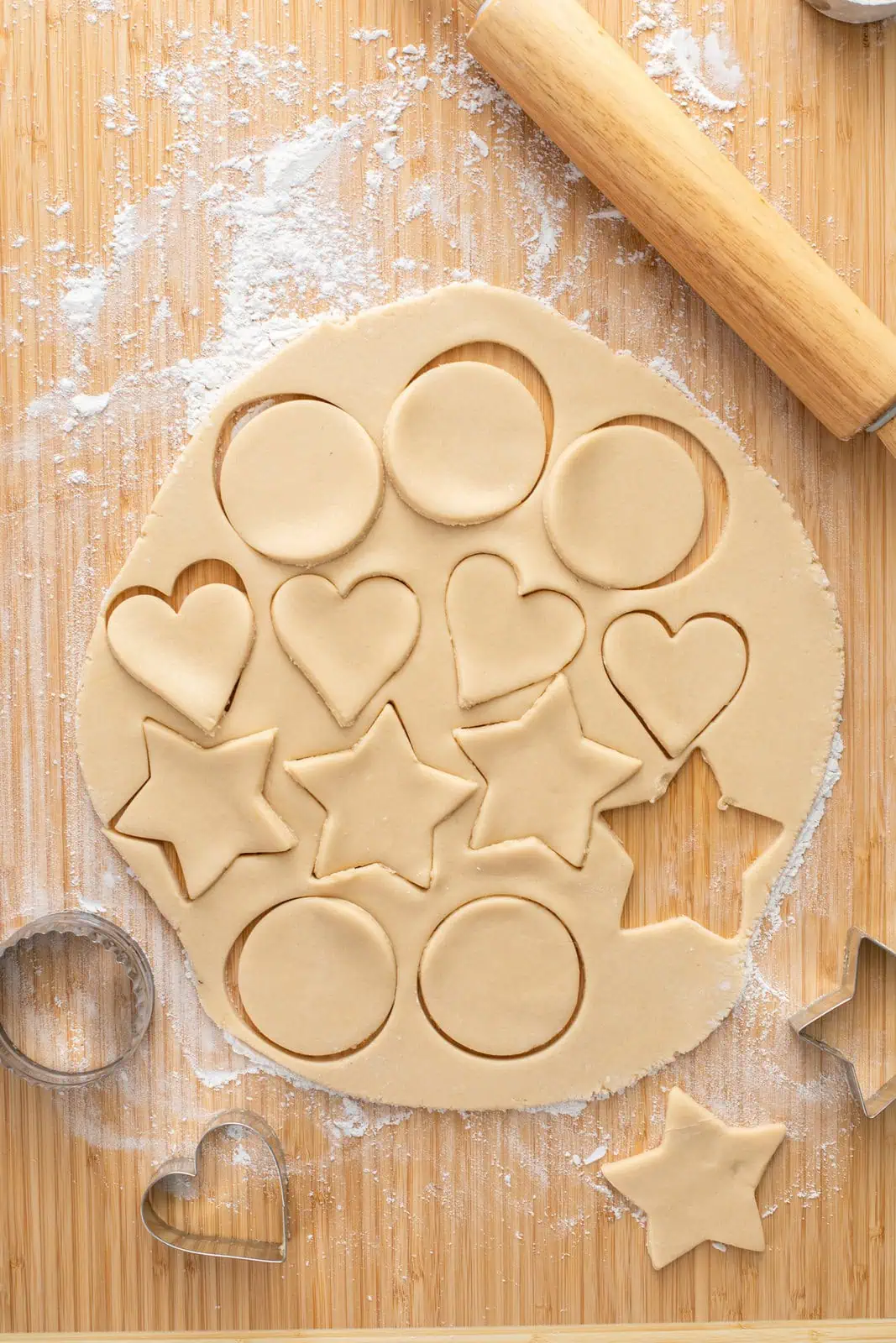 Shapes cut out of a circle of no chill sugar cookie dough on a floured board.