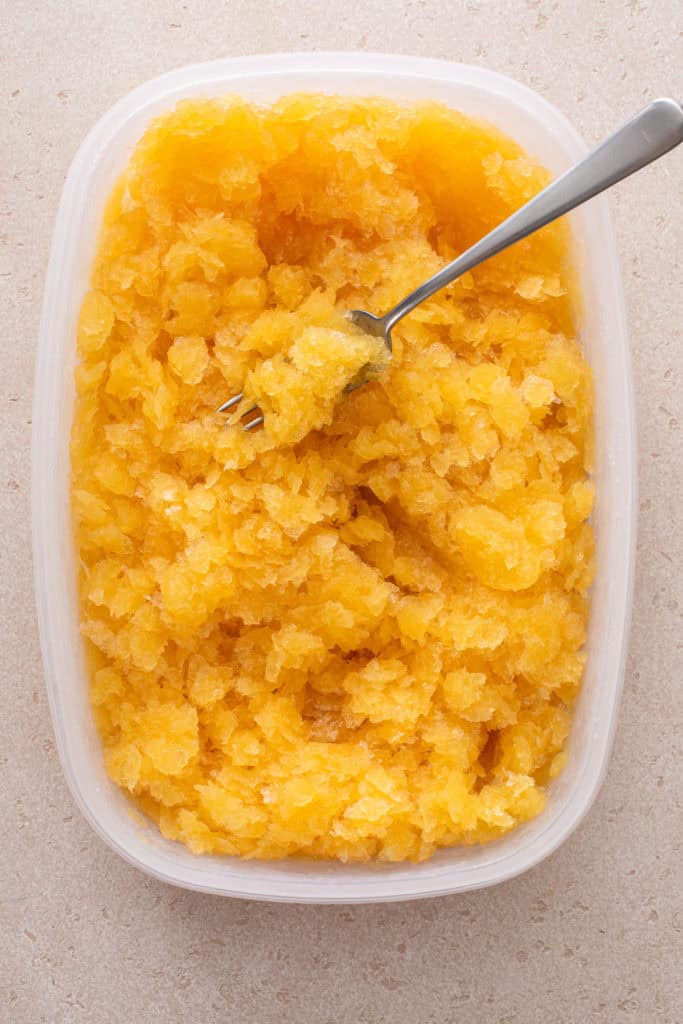 Fork scraping frozen bourbon slush in a container.