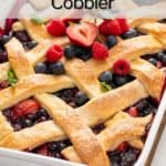 Lattice-topped berry cobbler in a white baking dish, garnished with fresh berries and fresh mint. Text overlay includes recipe name.