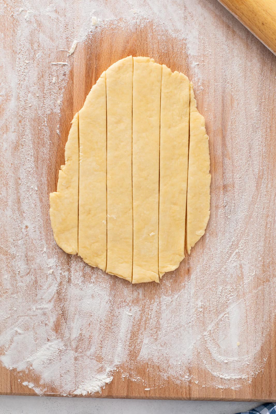 Portion of cobbler dough rolled onto a cutting board and cut into strips.