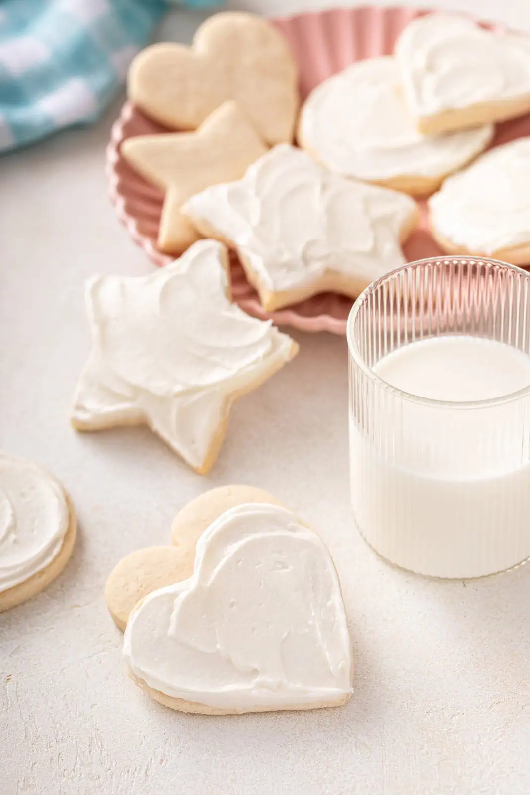 Several no chill sugar cookies scattered on a countertop next to a glass of milk.