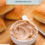 Bowl of cinnamon honey butter on a wooden board surrounded by dinner rolls. Text overlay includes recipe name.