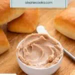 Bowl of cinnamon honey butter on a wooden board surrounded by dinner rolls. Text overlay includes recipe name.