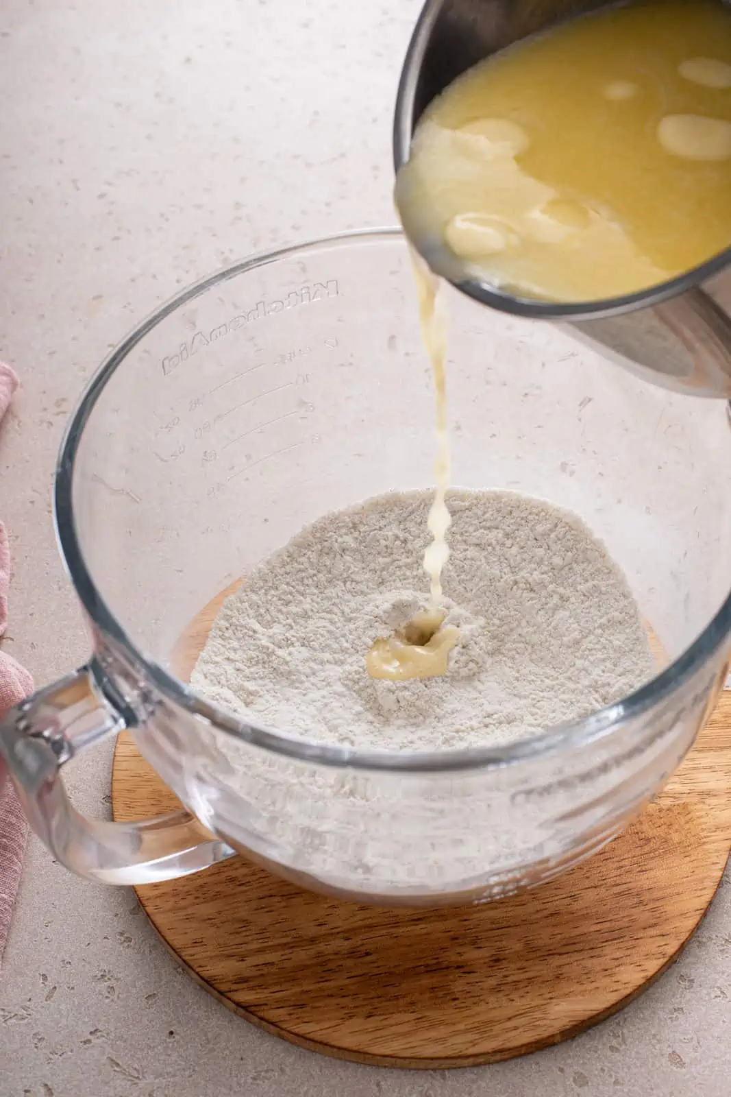 Wet ingredients being added to dry ingredients in a mixing bowl.