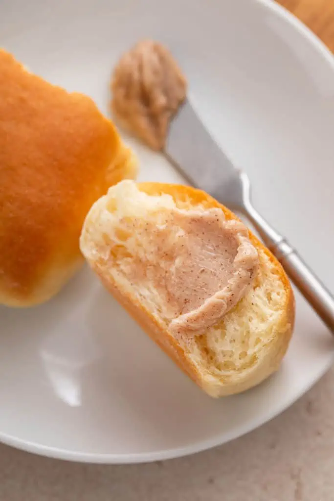 Close up of cinnamon honey butter spread onto a dinner roll.
