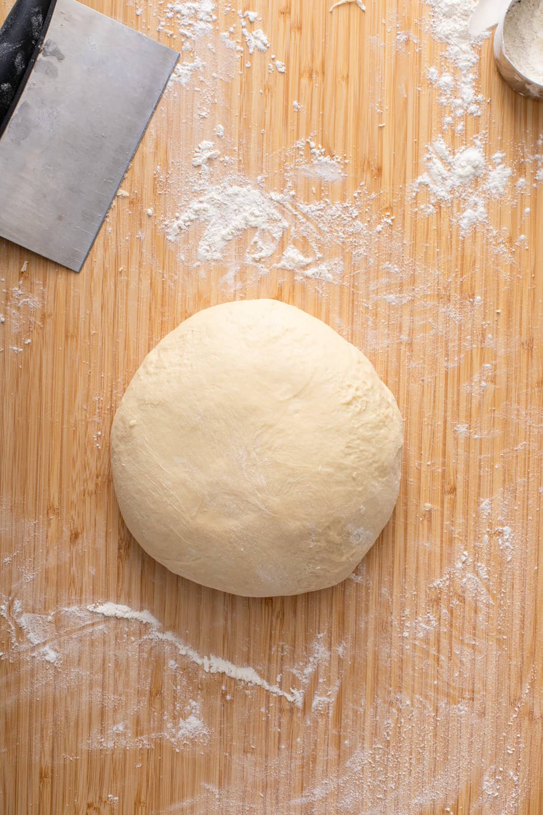 Kneaded texas roadhouse roll dough on a floured cutting board.