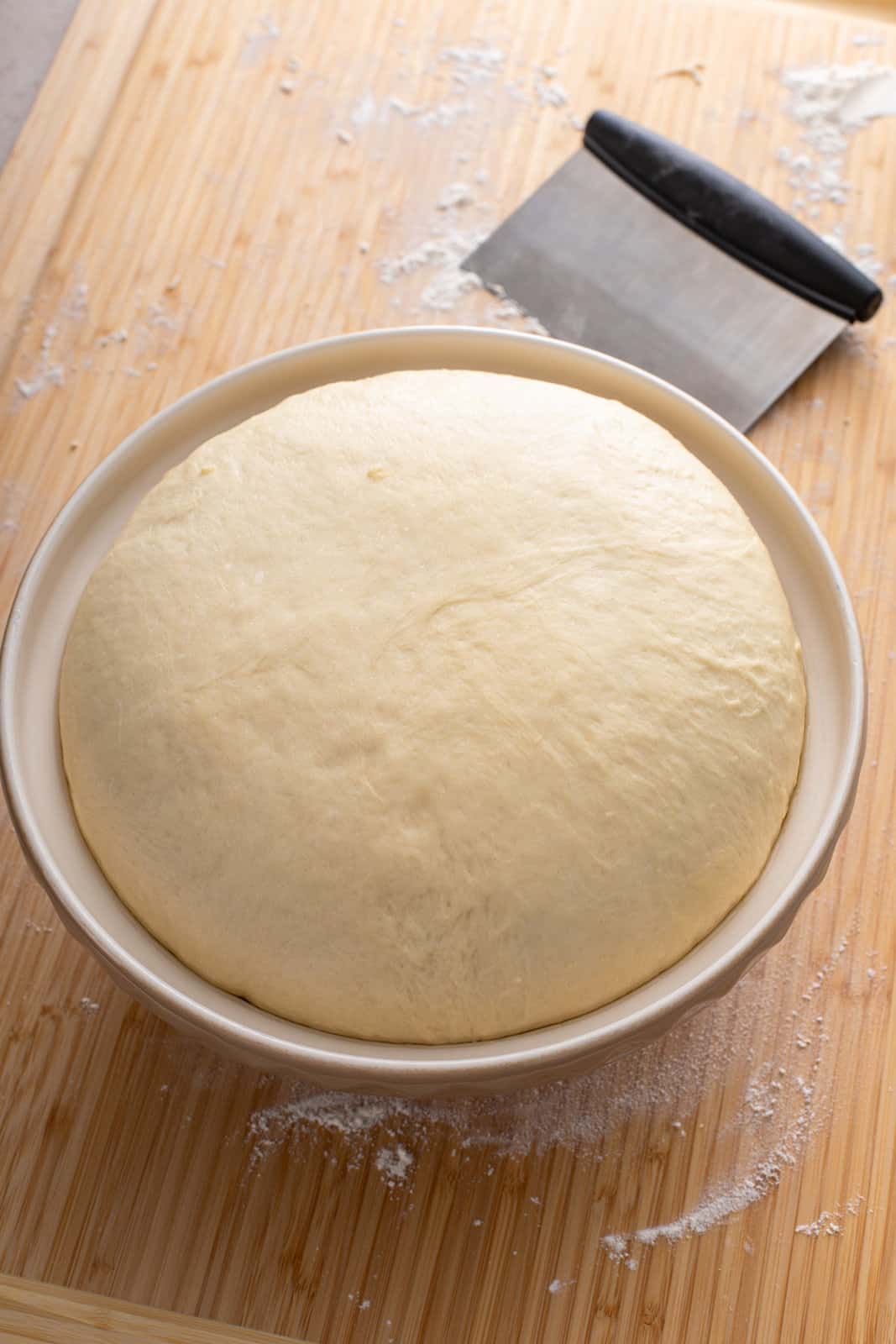 Risen texas roadhouse roll dough in a ceramic mixing bowl.