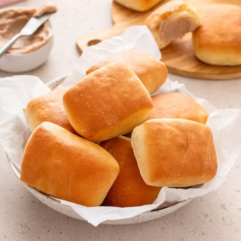 Close up of texas roadhouse rolls arranged in a bread basket on a beige countertop.