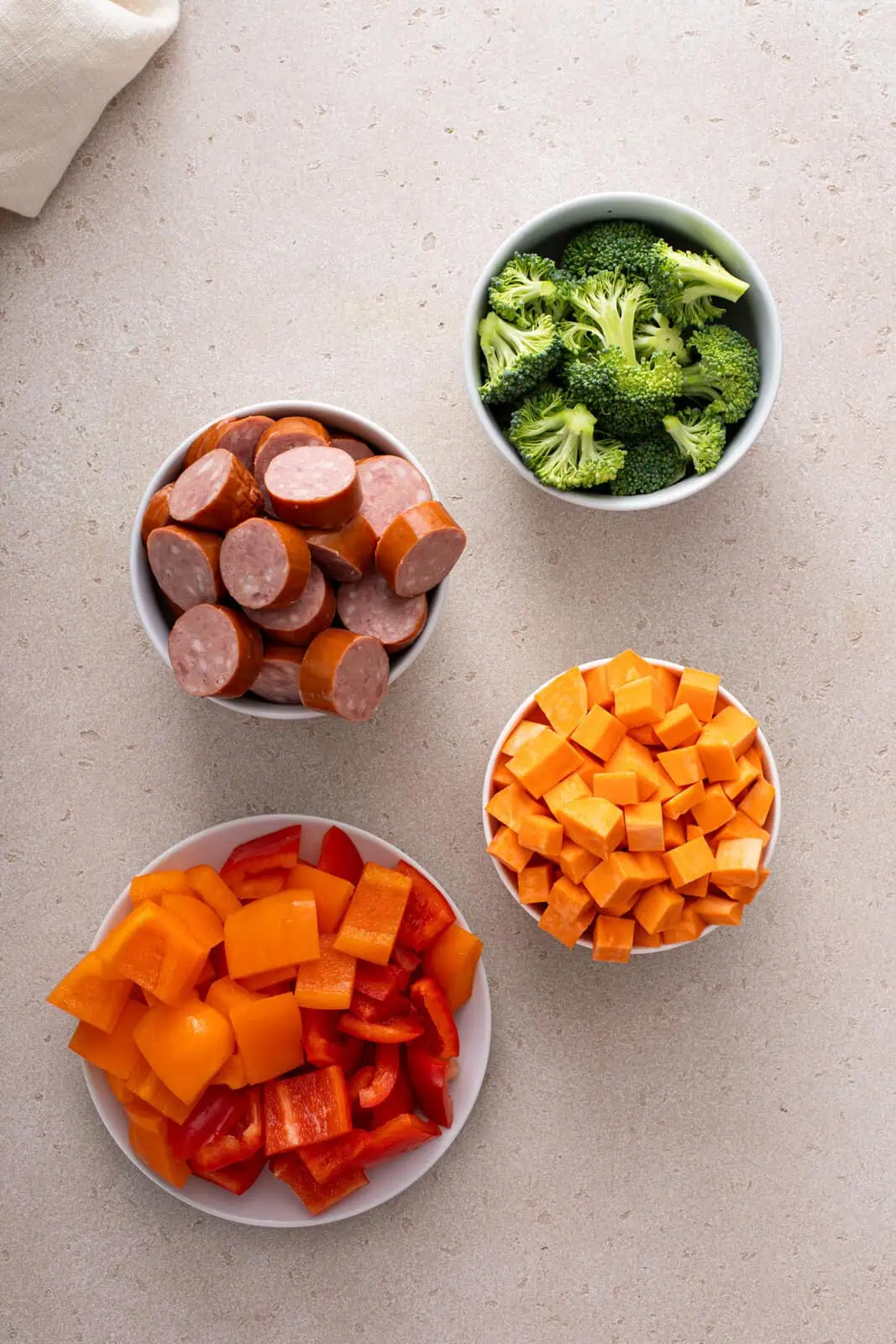 Bowls of sliced smoked sausage and cut-up vegetables.
