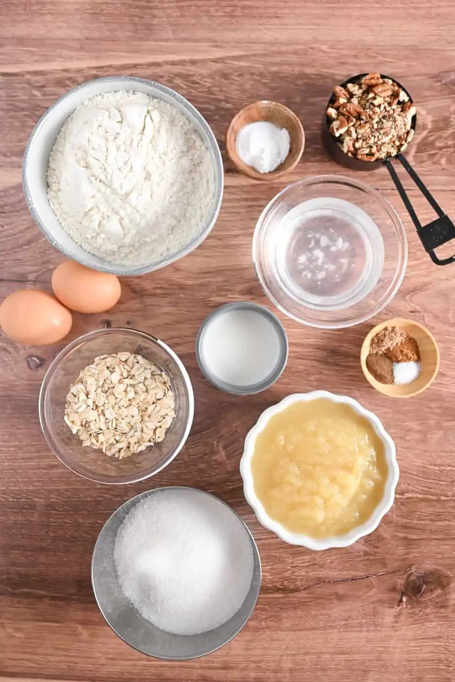 Ingredients for applesauce bread arranged on a wooden countertop.