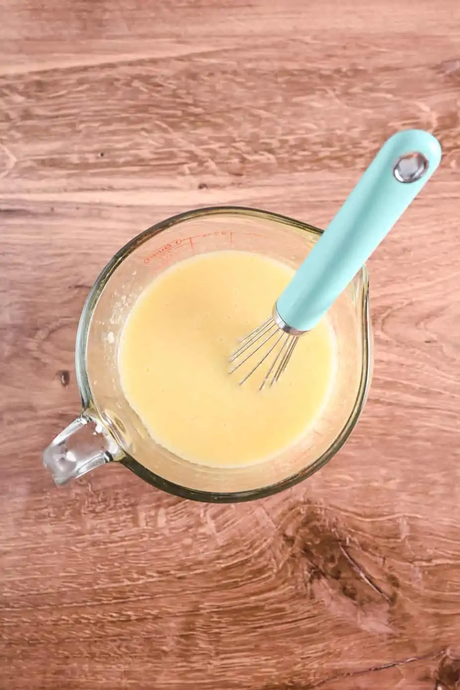 Wet ingredients for applesauce bread in a glass measuring cup.