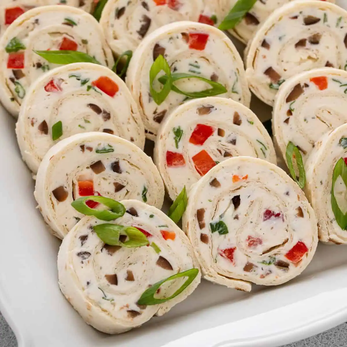 Close up of sliced cream cheese ranch roll ups on a white platter.