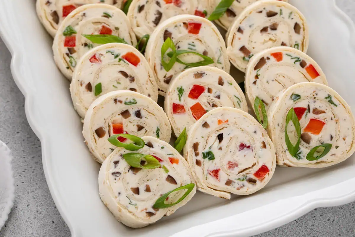 Close up image of cream cheese ranch roll ups lined up on a platter.