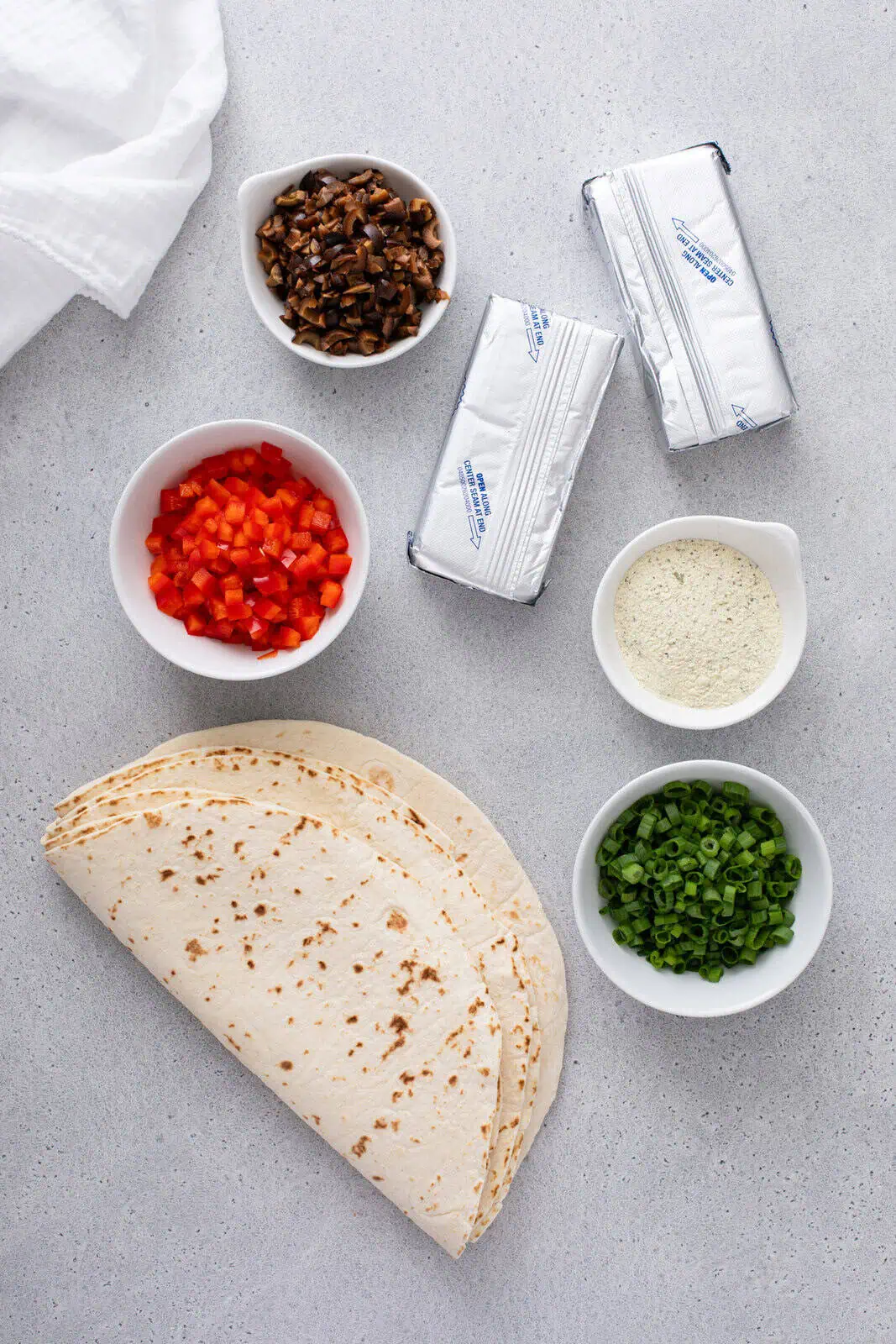 Cream cheese ranch roll up ingredients arranged on a countertop.