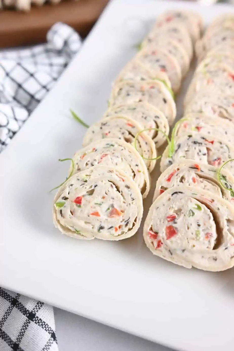 Close up of cream cheese pinwheels on a white platter.