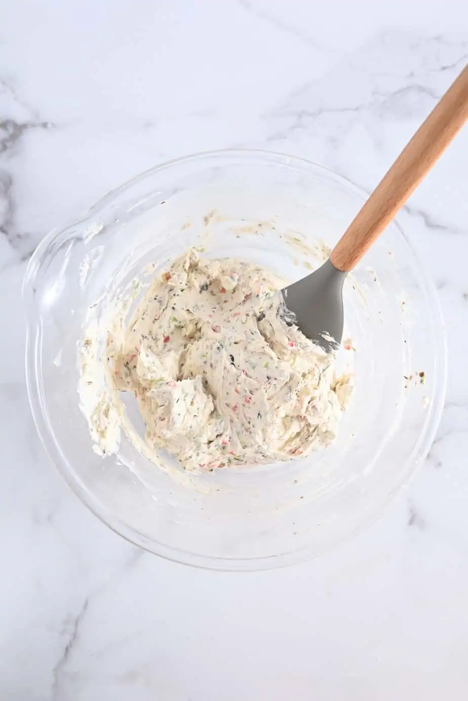 Cream cheese filling for ranch roll ups being stirred in a glass bowl.