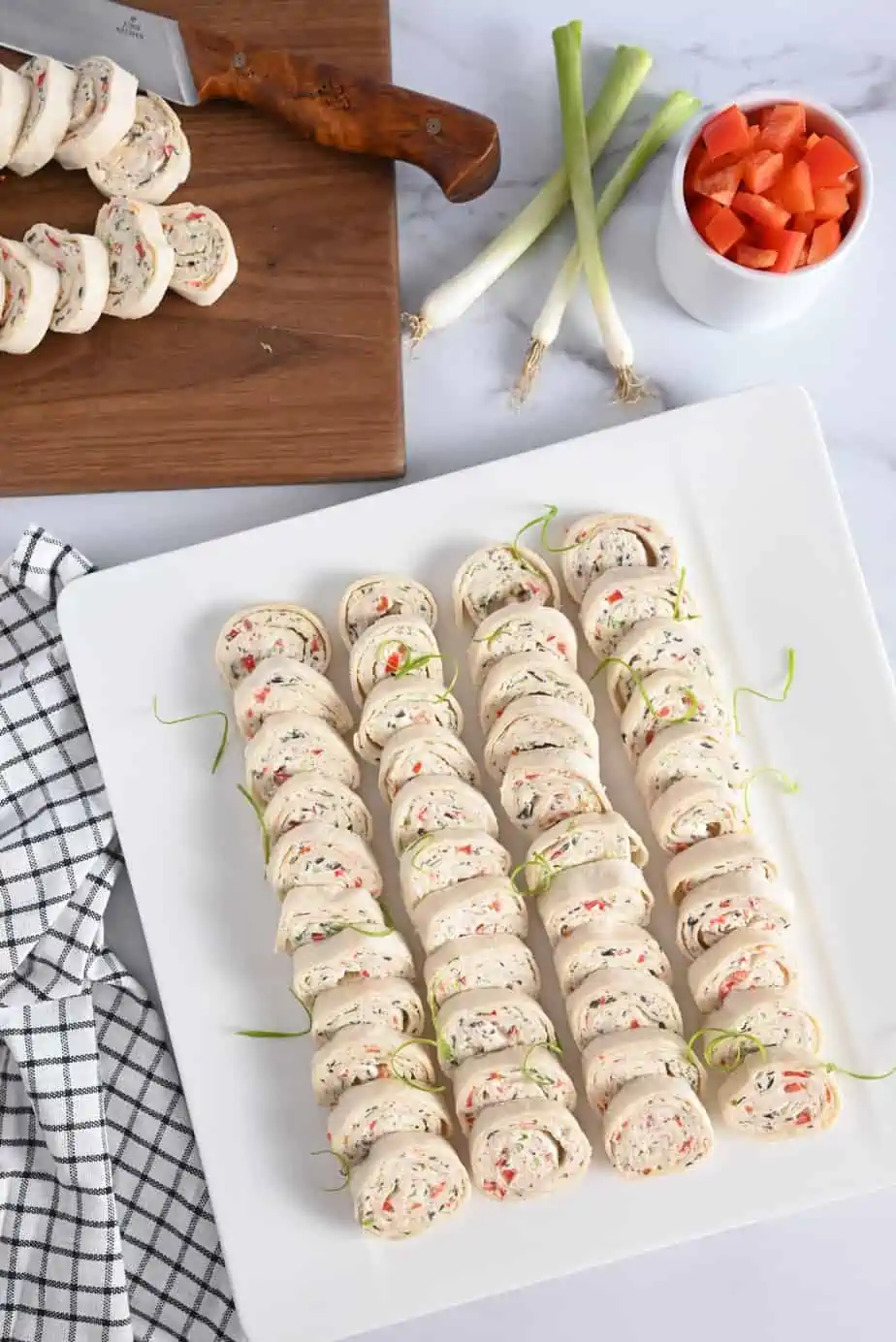 Overhead view of cream cheese roll ups arranged on a white platter.