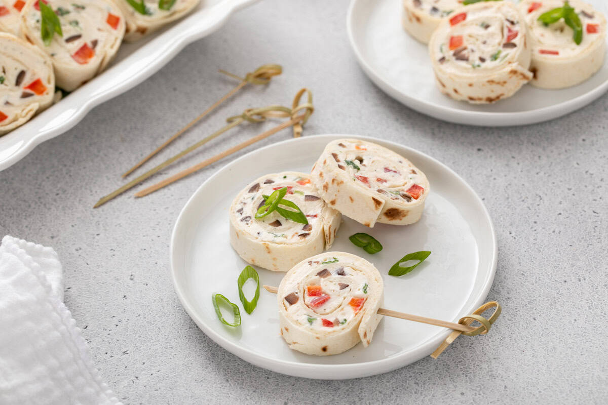 Three cream cheese ranch roll up slices arranged on a white plate.