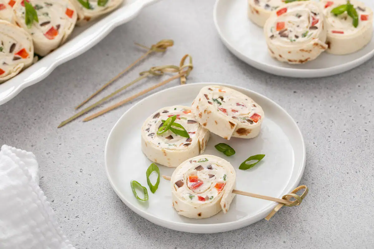 Three cream cheese ranch roll up slices arranged on a white plate.