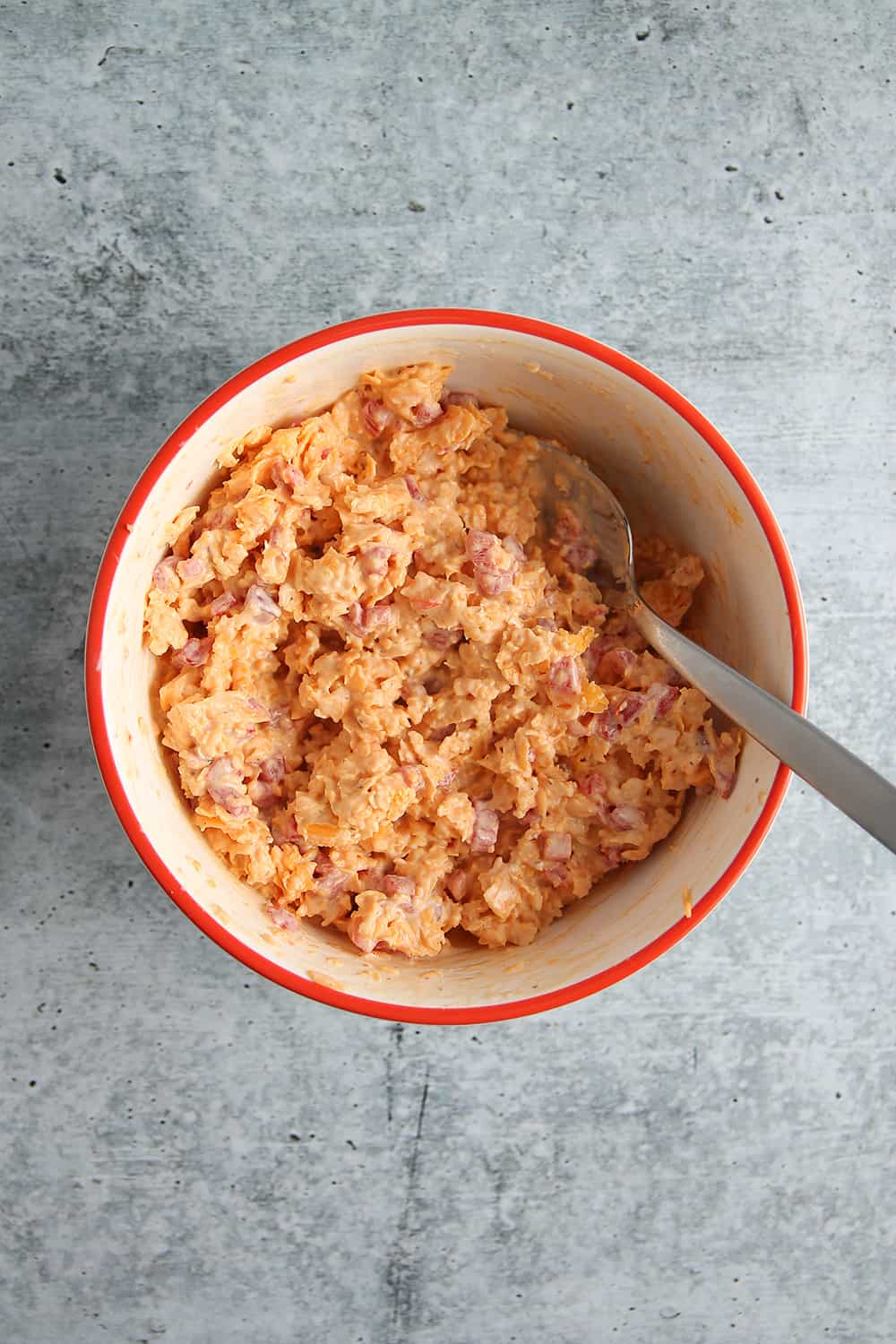 Overhead view of pimento cheese in a bowl with a spoon