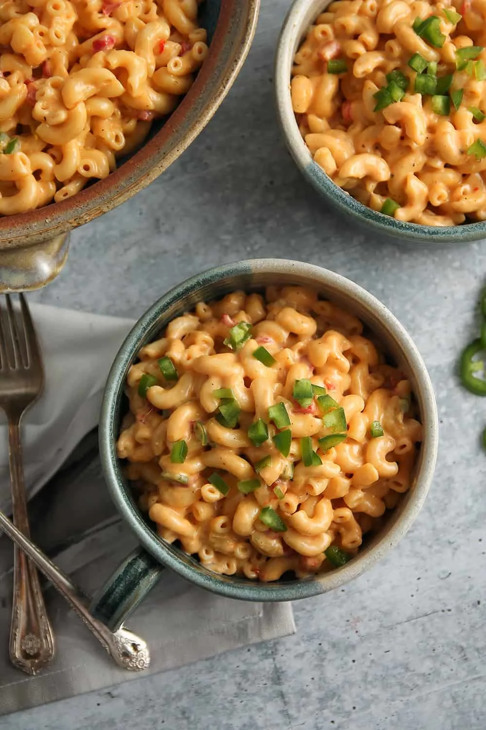 Overhead view of green chili macaroni and pimento cheese in serving bowls on concrete surface