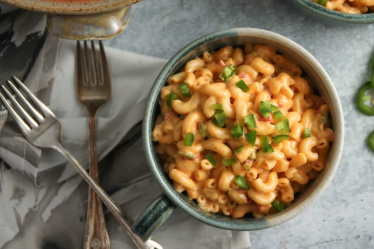 Small bowl of macaroni and pimento cheese next to two crossed forks