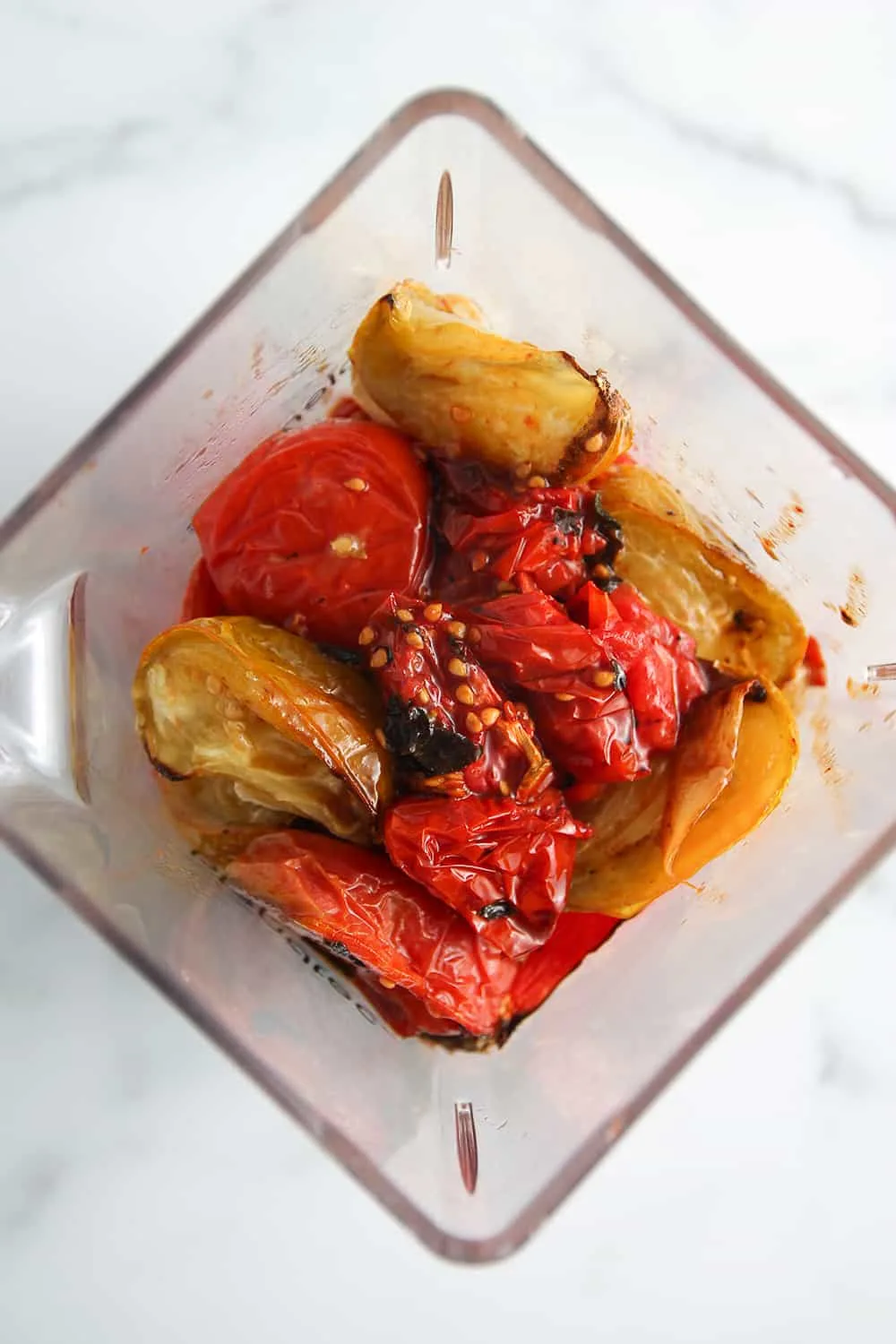 Overhead view of roasted tomatoes in a blender, ready to be made into sauce