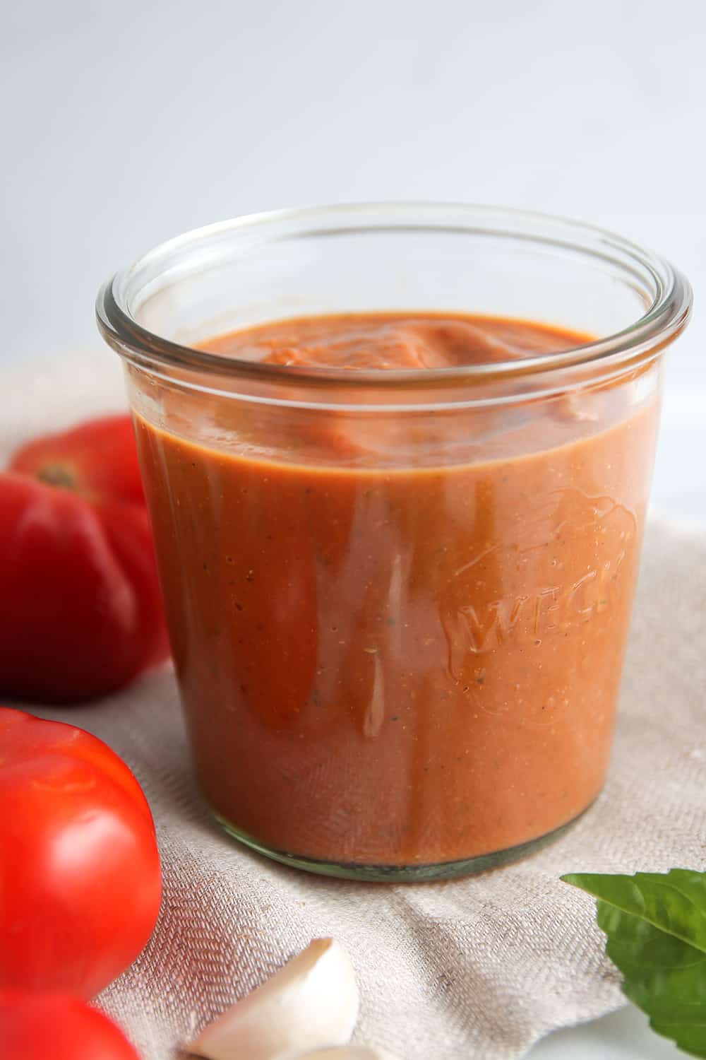Roasted tomato sauce in a jar, next to fresh tomatoes