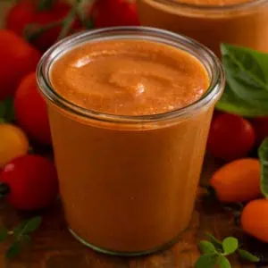 Side view of a glass jar filled with roasted tomato sauce.