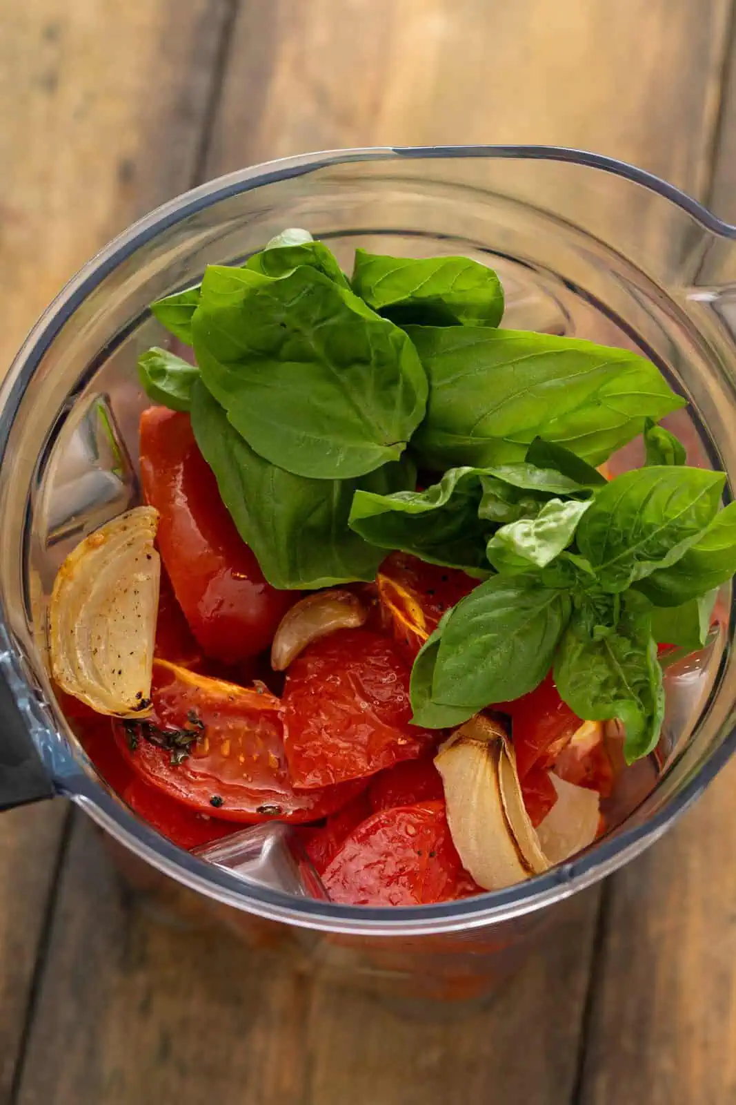 Roasted tomatoes and onions and fresh basil added to a blender jar.