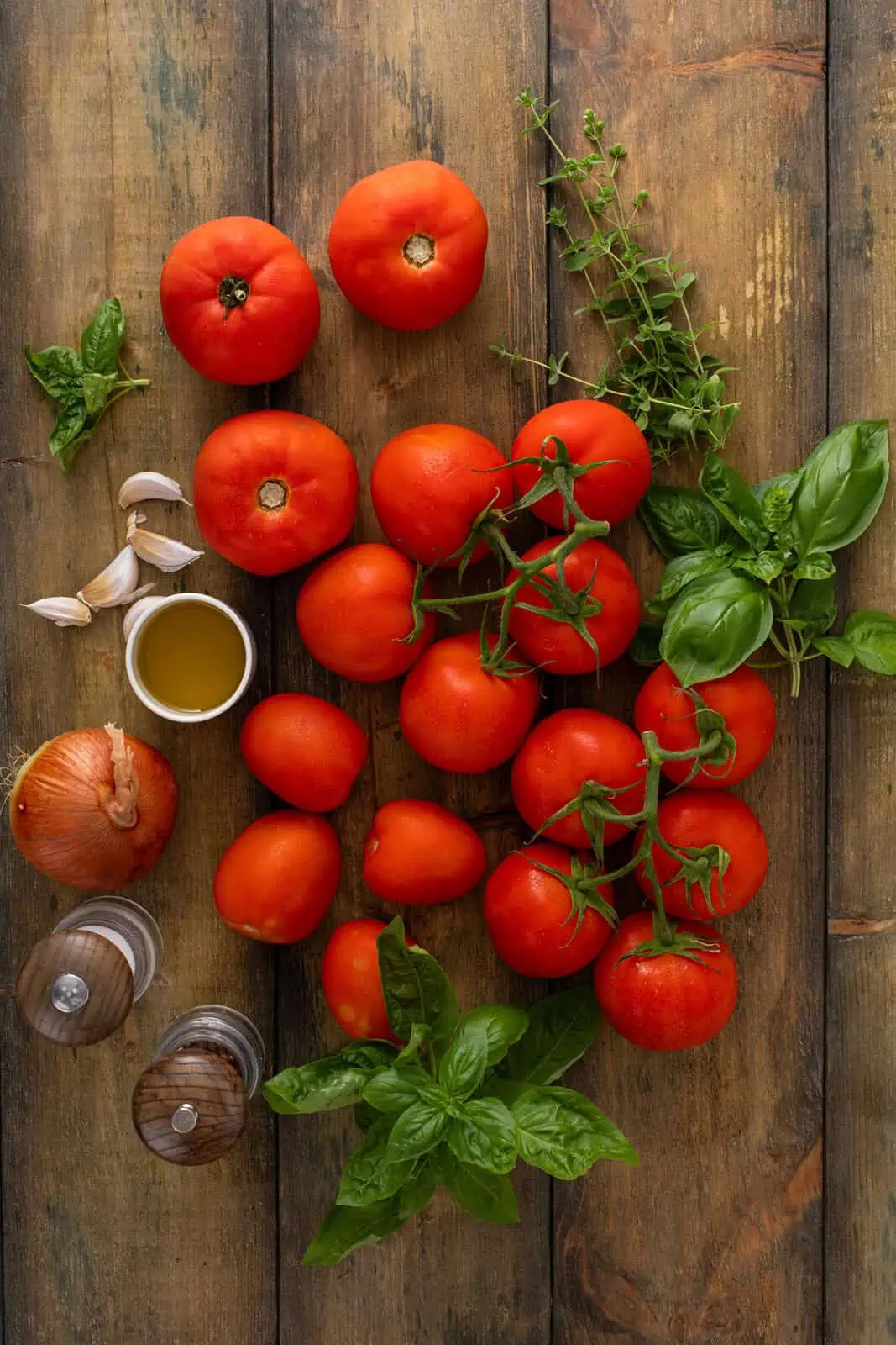 Ingredients for roasted tomato sauce arranged on a wooden table.