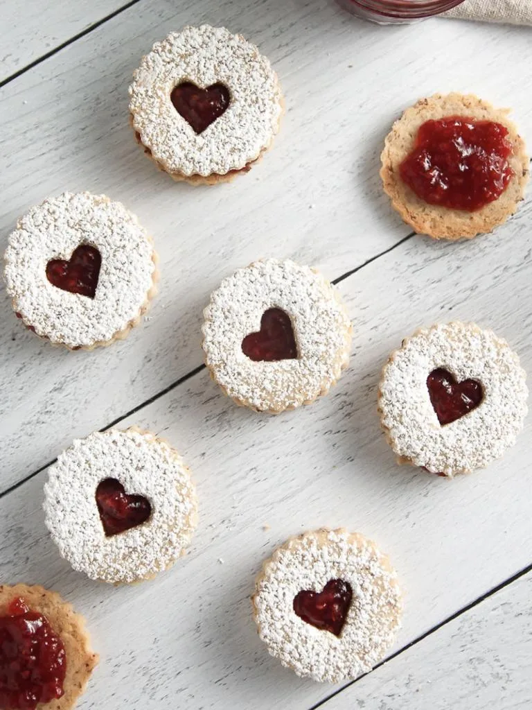 Raspberry Linzer Cookie sandwiches on a white surface