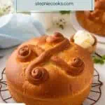 Cooled loaf of paska on a wire rack. a second loaf, a bowl of butter, and a small jug of milk are in the background. Text overlay includes recipe name.