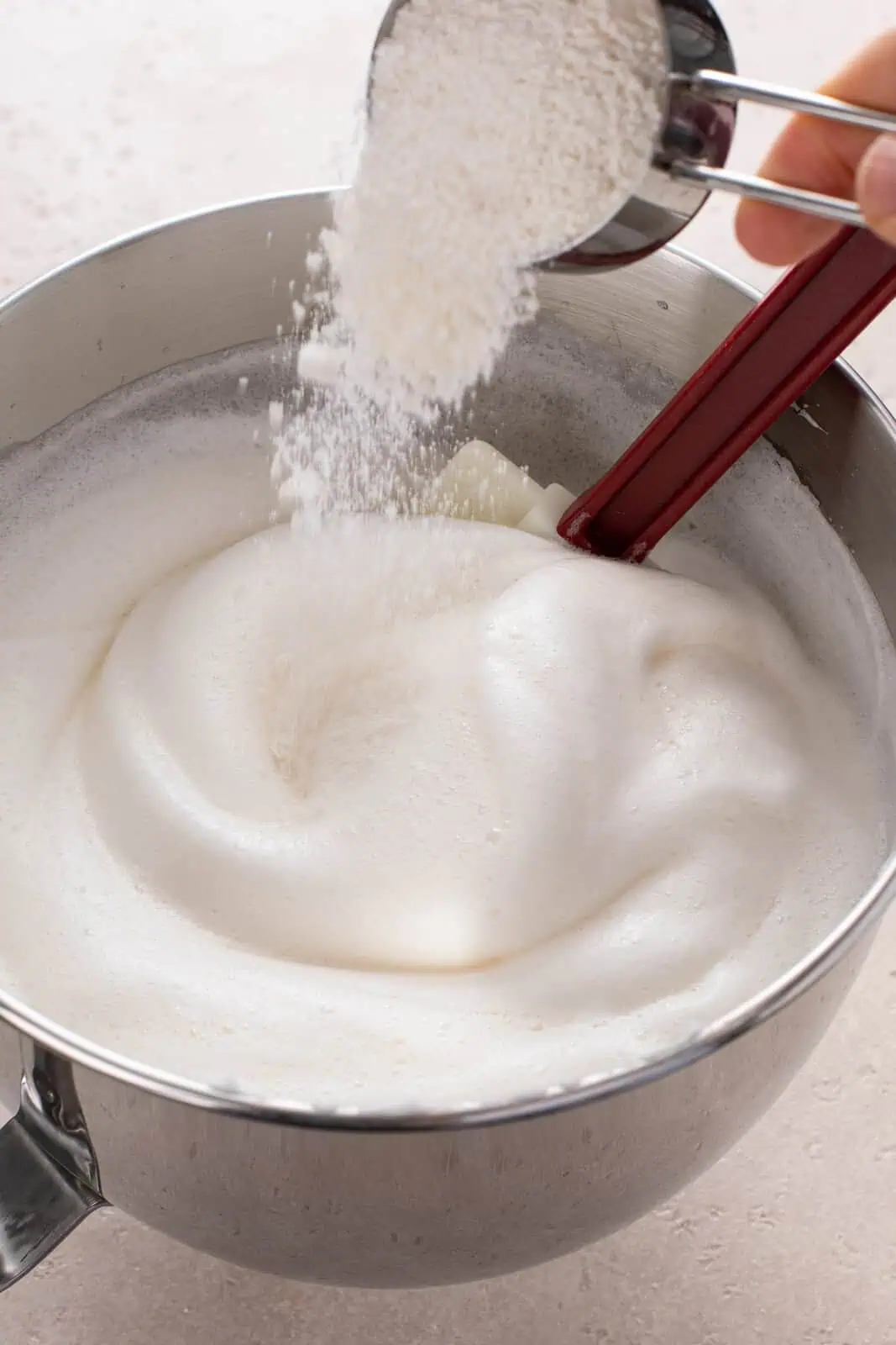 Sifted flour being sprinkled over the top of egg white batter.