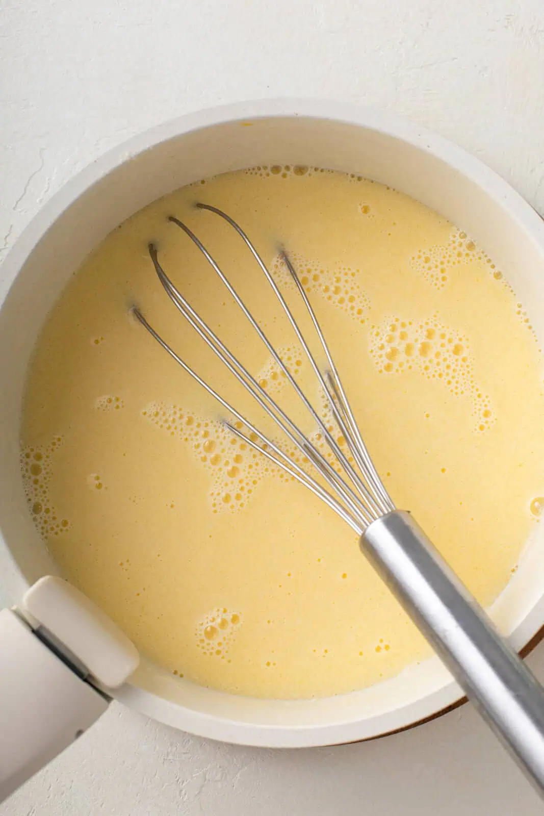 Eggs whisked into scaled milk and melted butter in a saucepan.