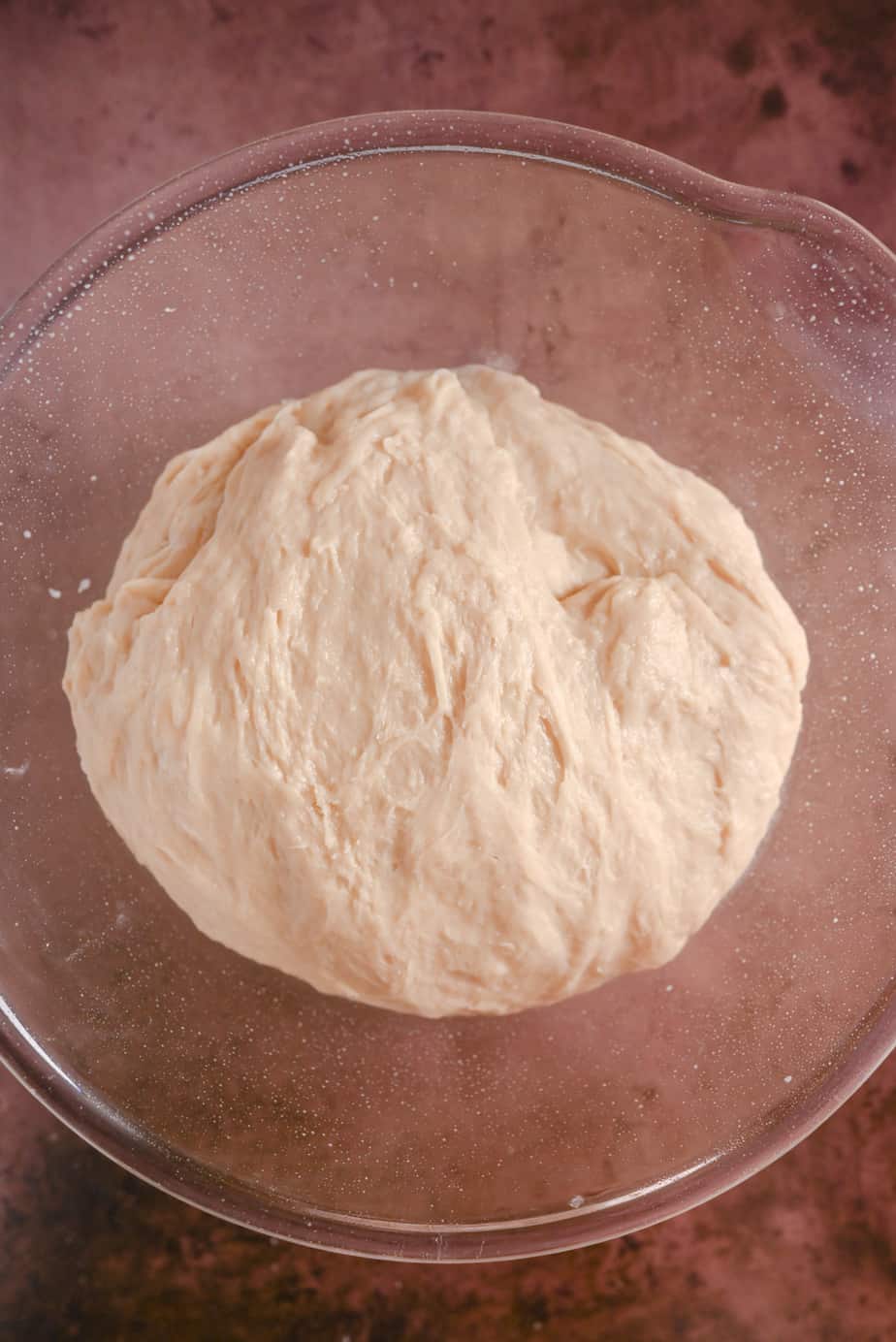 Kneaded paska dough in a greased glass mixing bowl