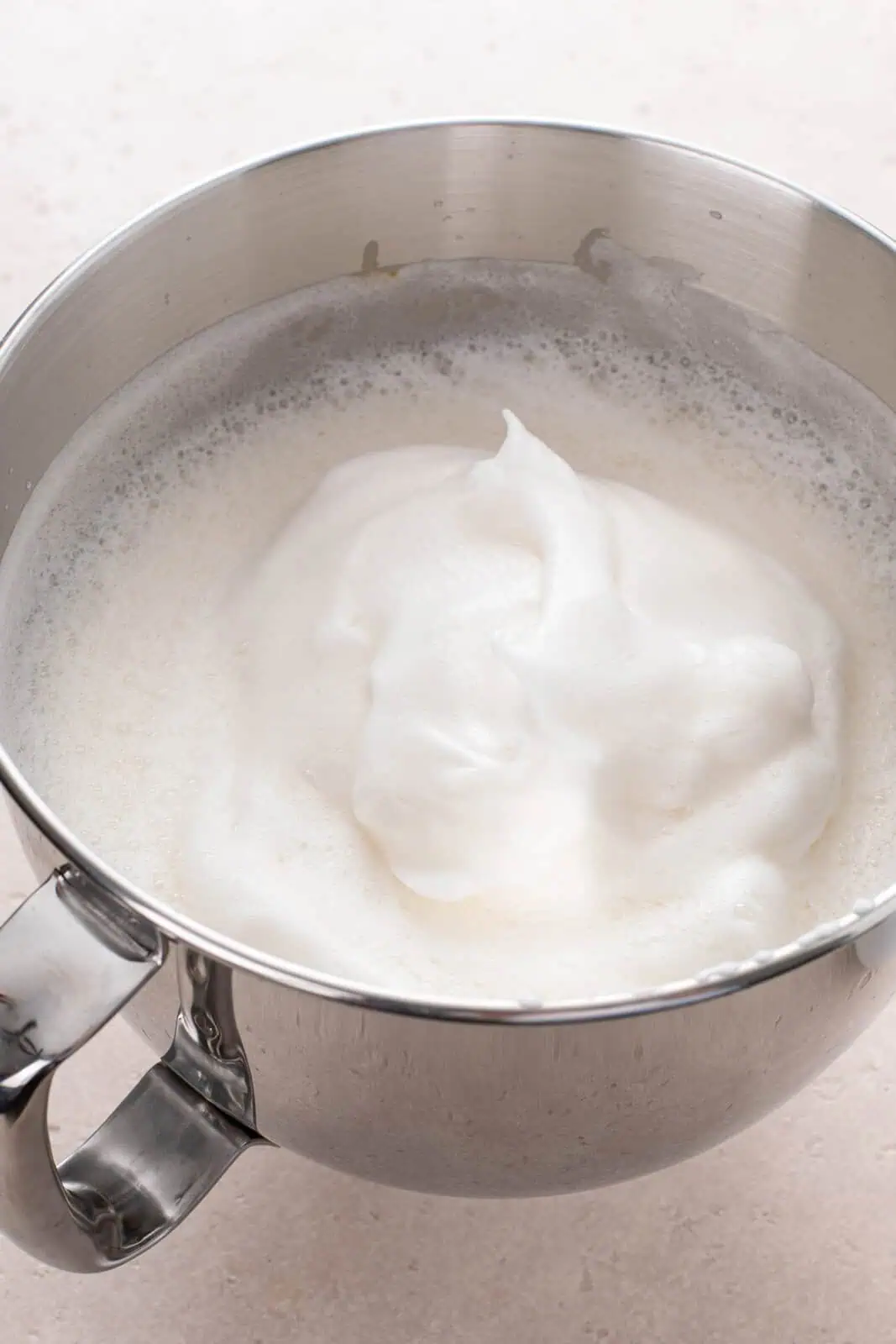 Egg whites beaten to medium peaks in a metal bowl.