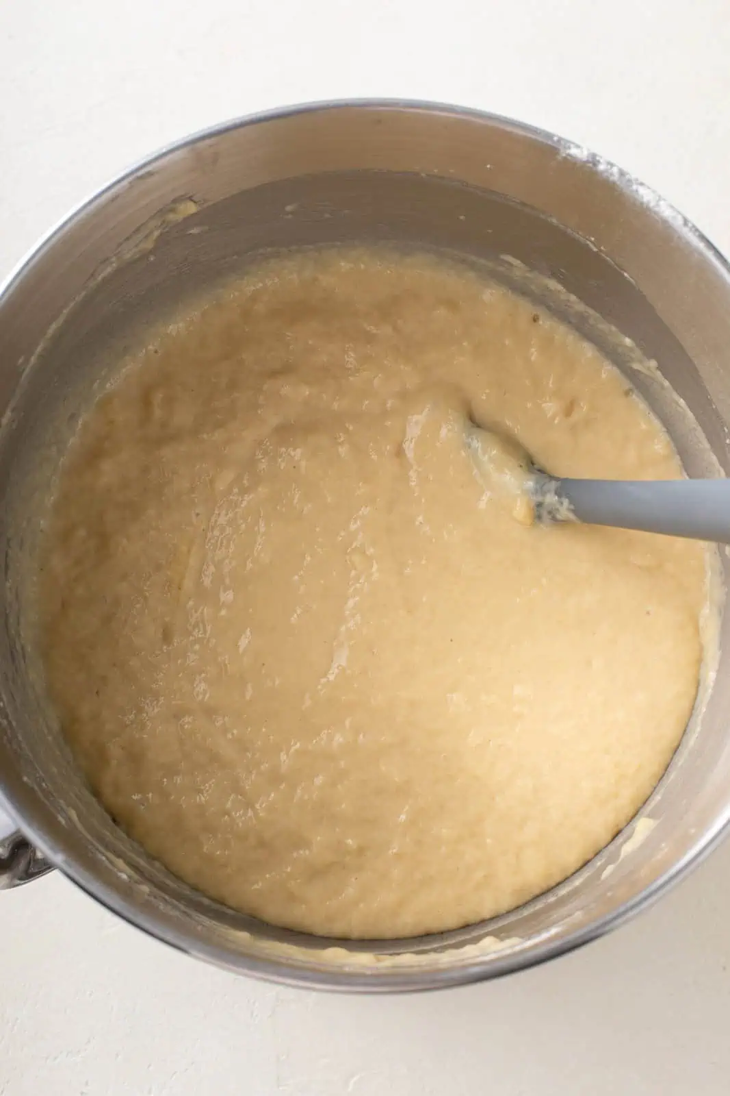 Flour mixed into the wet ingredients for paska dough in the bowl of a stand mixer.