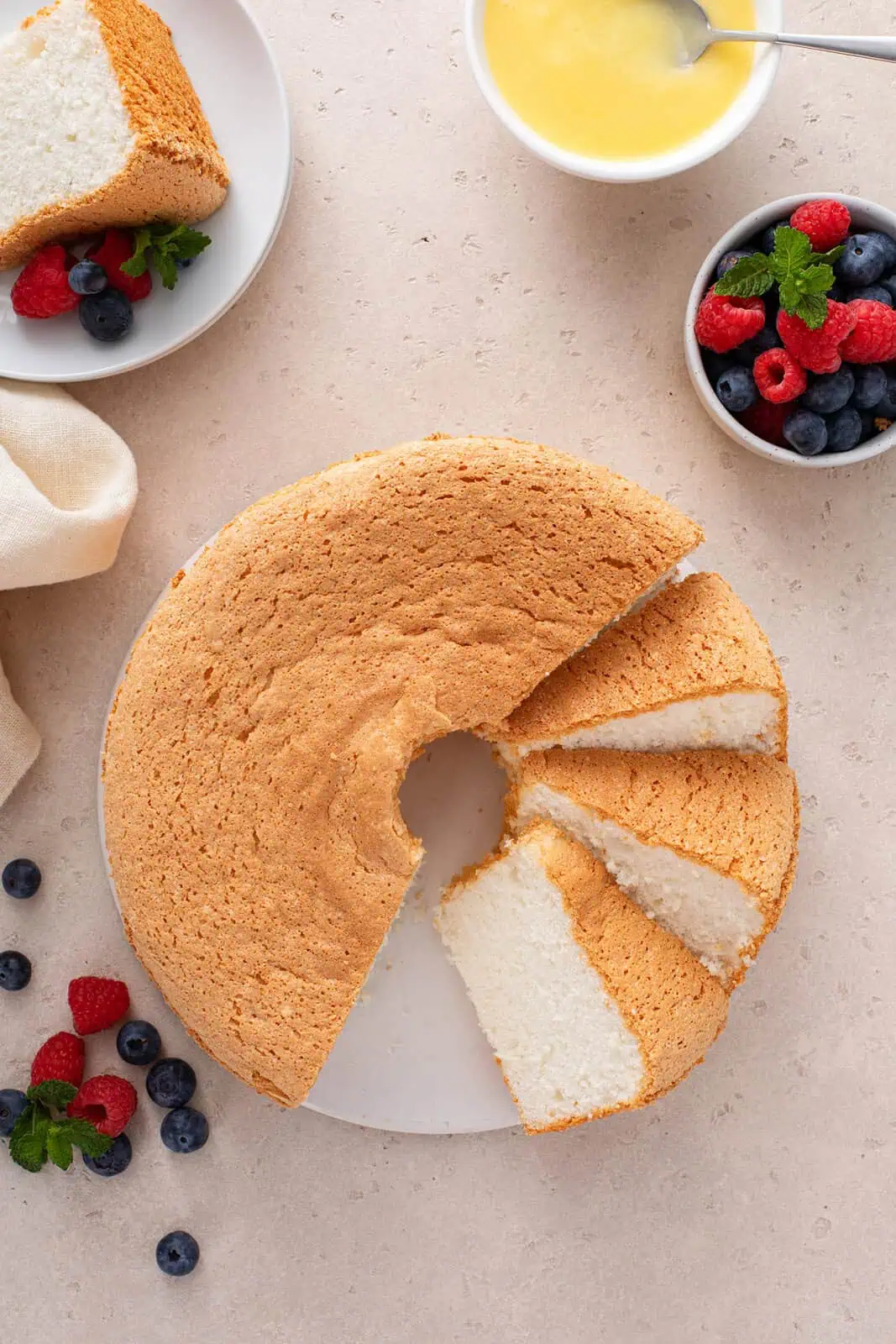 Overhead view of angel food cake on a cake plate, with half of the cake cut into slices.