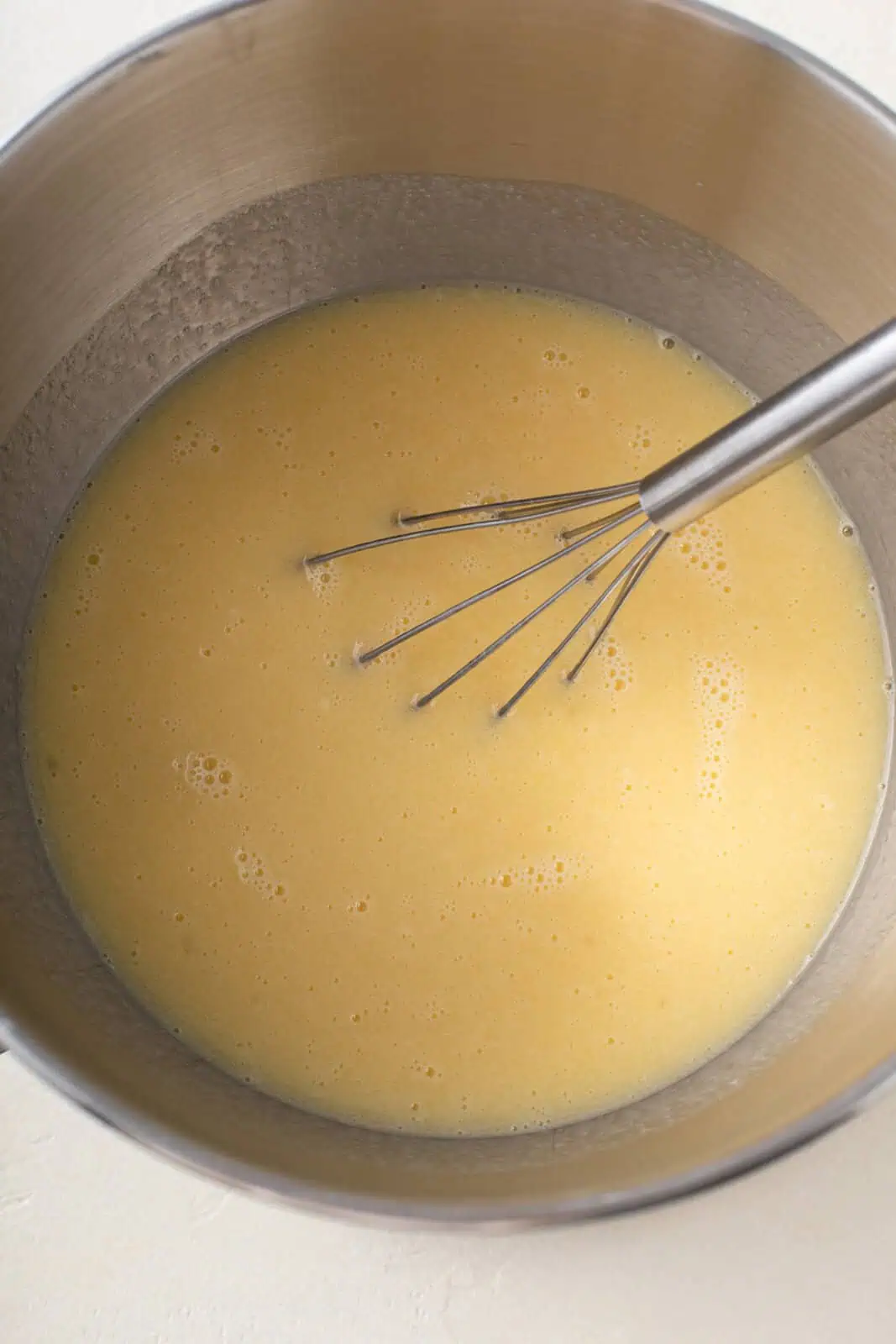 Wet ingredients for paska whisked in the bowl of a stand mixer.