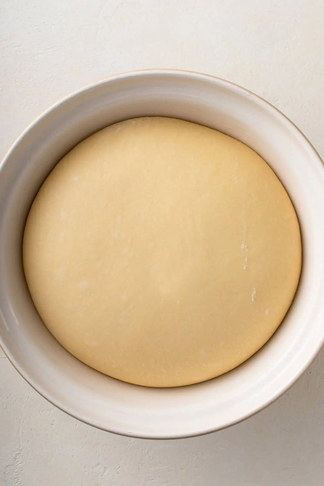 Risen paska dough in a white bowl, ready to be shaped into loaves.