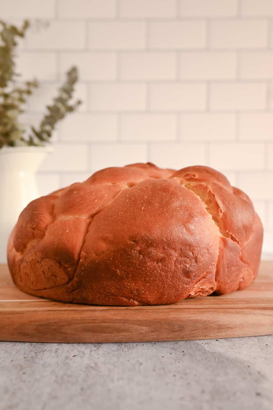 Side view of a loaf of paska on a wooden board