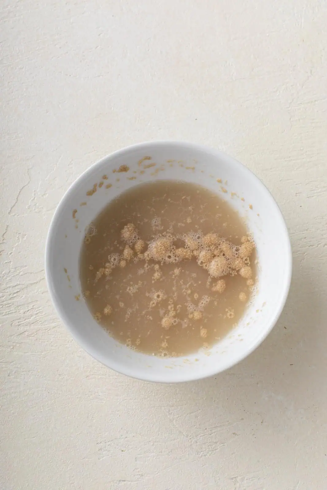 Active dry yeast dissolved in water in a small bowl.