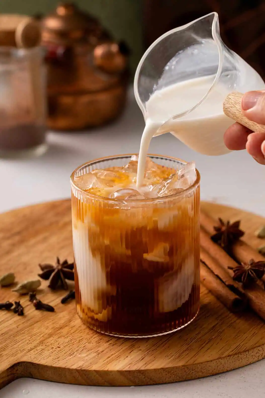 Cold milk being added to a glass filled with chai concentrate and ice.