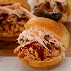 Pulled chicken slider topped with slaw and a pickle.