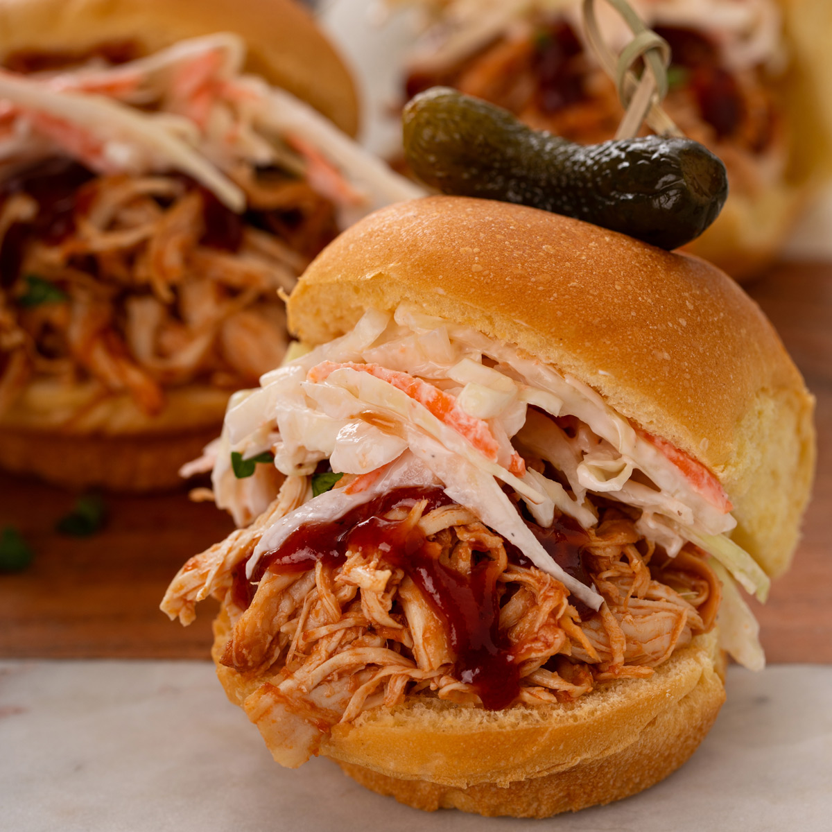 Pulled chicken slider topped with slaw and a pickle.