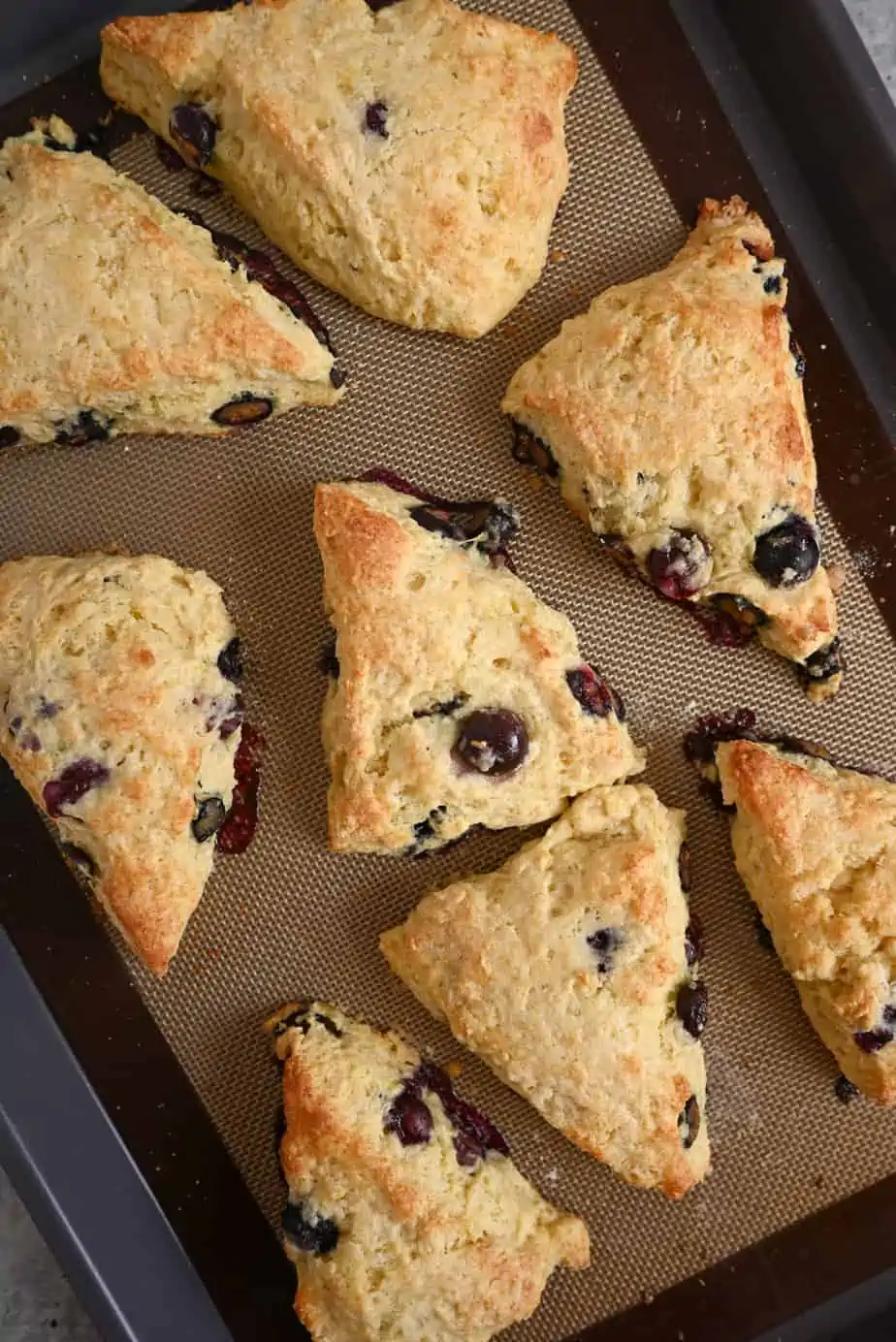 Baked blueberry lemon scones on a lined baking sheet.