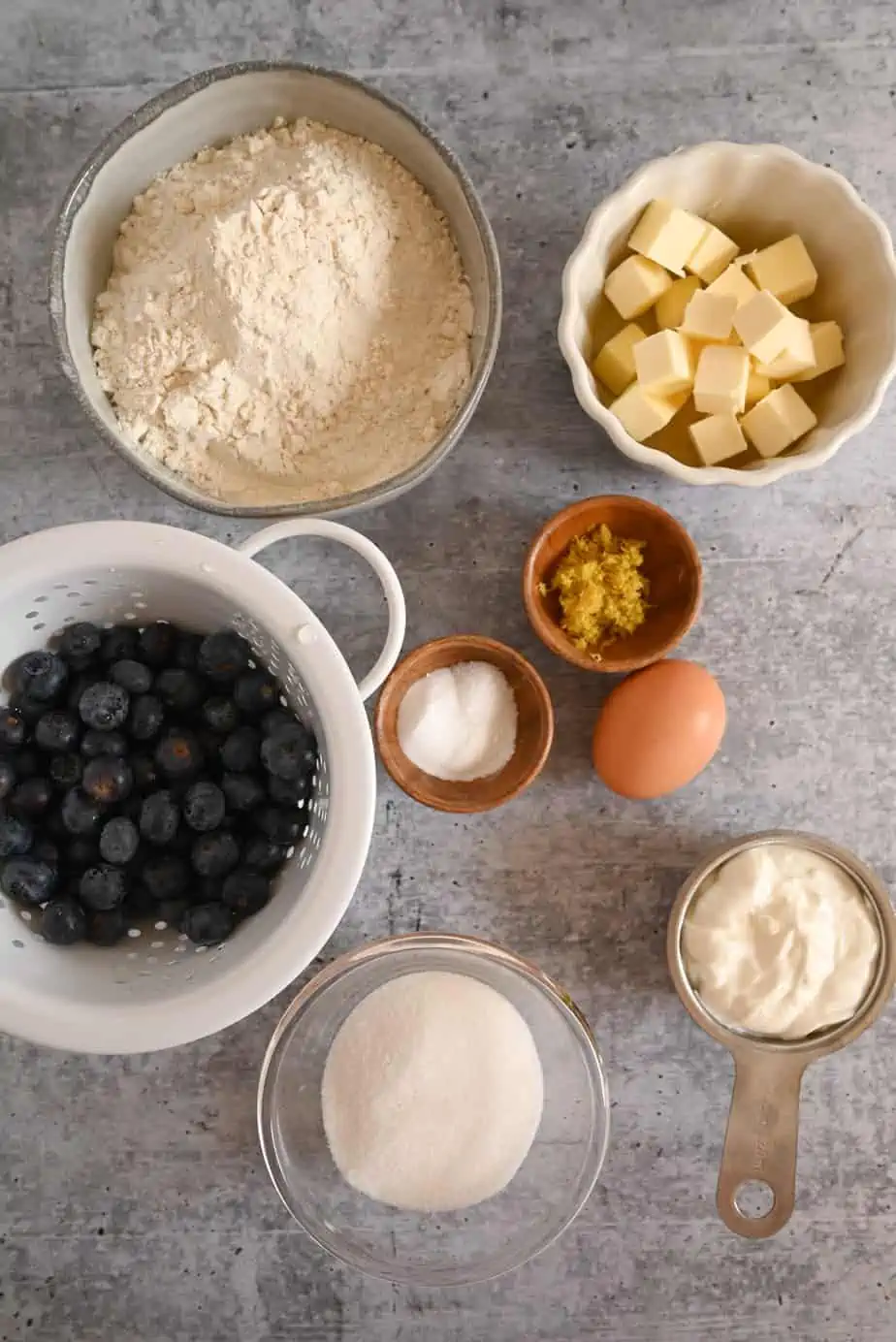 Ingredients for blueberry lemon scones arranged on a gray countertop.