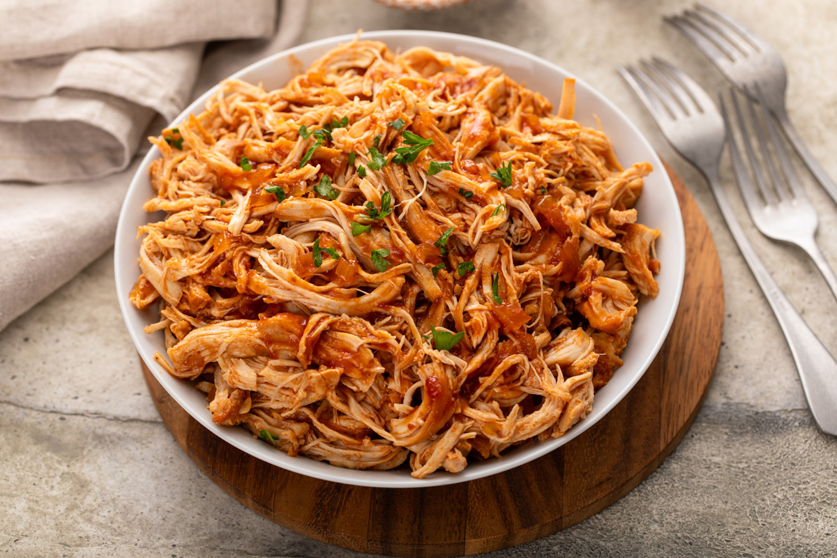 Pulled BBQ chicken in a white serving bowl.