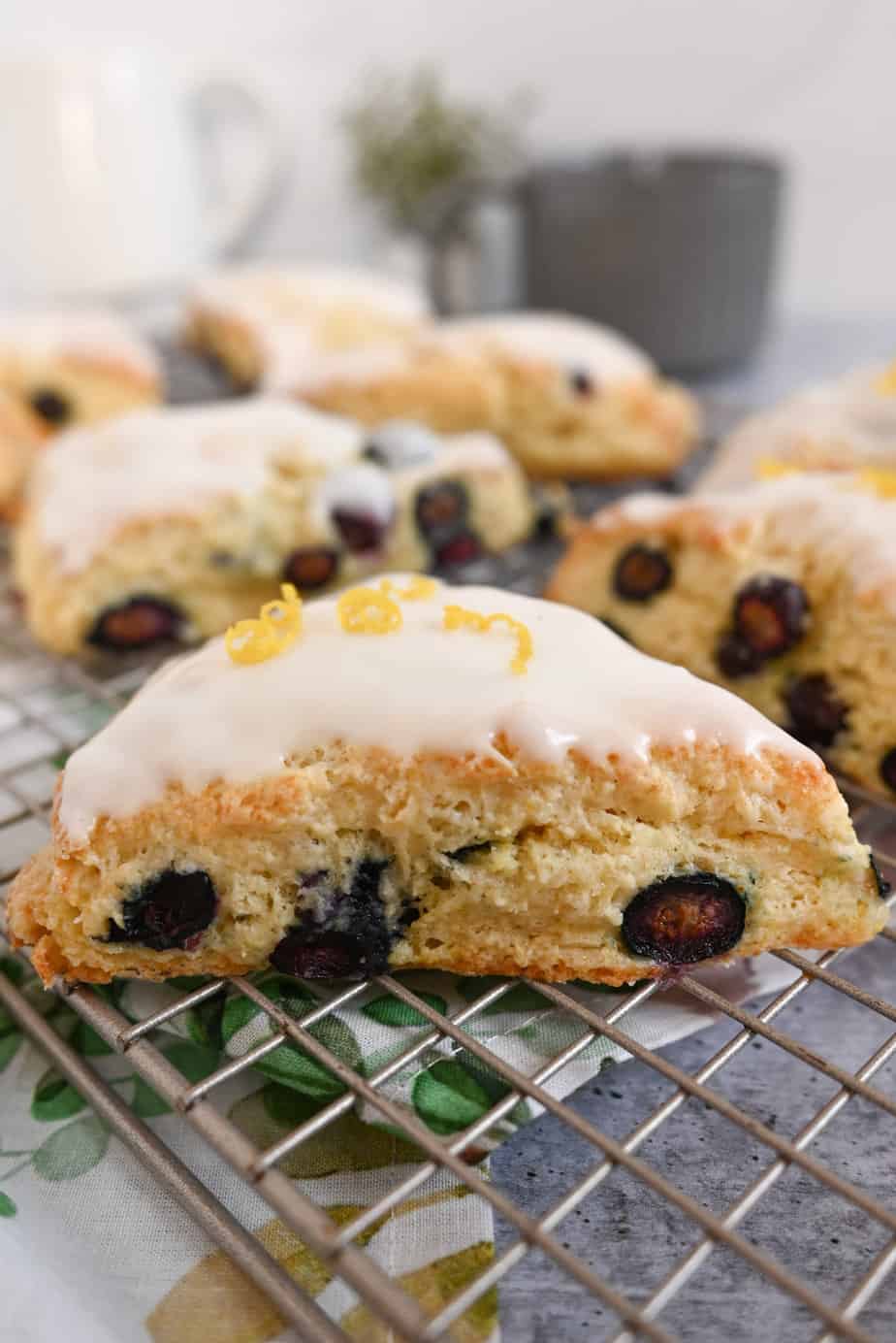 Blueberry lemon scones topped with lemon glaze set on a wire cooling rack.